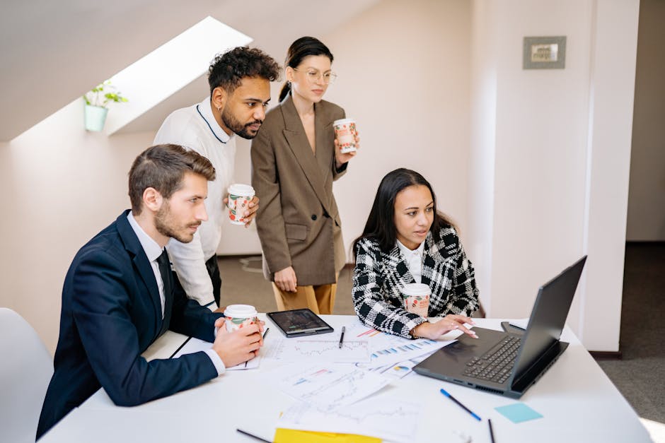 A diverse team collaborates in a modern office, using laptops and tablets for planning and brainstorming