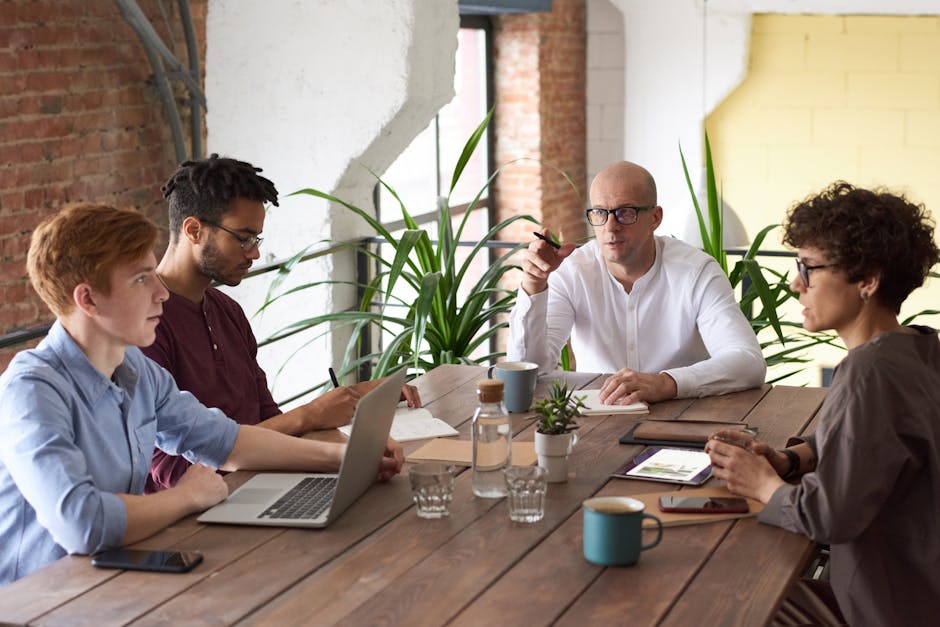 Business professionals collaborating in a modern office with laptops and plants on a wooden table